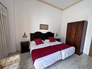 a bedroom with a large bed with red pillows at Hotel Bodega el Moral in Ribera del Fresno