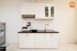 a kitchen with white cabinets and a sink at Merry House Bạch Dương in An Khê