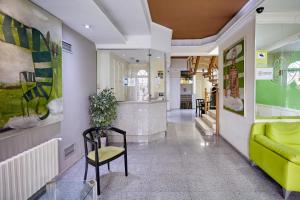 a hallway with a green couch and a chair at Hotel Zaymar in Castellón de la Plana