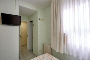 Habitación con cama, TV y ventana. en Hotel Zaymar, en Castellón de la Plana