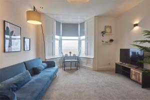 een woonkamer met een blauwe bank en een tafel bij 5 Roker Terrace - Seaview apartments in Sunderland