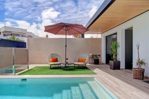 een patio met een tafel en een parasol naast een zwembad bij Villa Toro in Corralejo