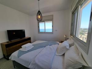 a bedroom with a bed and a tv and a window at Ducks on the beach in Acre