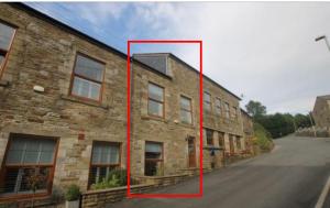 a large brick building with a red rectangle next to a street at Double Room with en-suite shower and juliet balcony in Rossendale