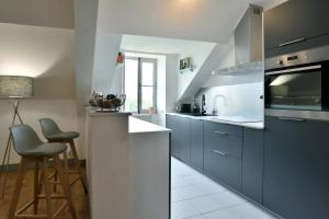uma cozinha com armários azuis e um balcão com bancos em Le Sainte Catherine - Appt centre-historique em Dinan