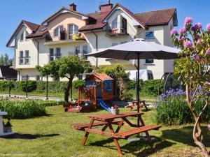 a picnic table and an umbrella in front of a house at Dom Wczasowy BiuLux in Mielno