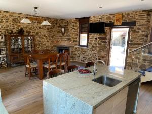 eine Küche und ein Esszimmer mit einem Waschbecken und einem Tisch in der Unterkunft Casa Amada con piscina in Murias de Pedredo