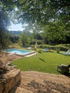 a swimming pool in a grassy yard with a tree at Locations insolites "vie en plein air" cabane Bastide Bellugue maison d'hôtes reseau Bienvenue à la ferme à 3 mn de lourmarin in Cadenet