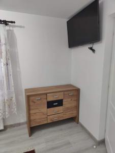 a wooden dresser with a flat screen tv on a wall at Casa Godja Oncesti in Onceşti