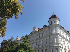 ein weißes Gebäude mit einem Turm darüber in der Unterkunft Das Domizil in Klagenfurt am Wörthersee