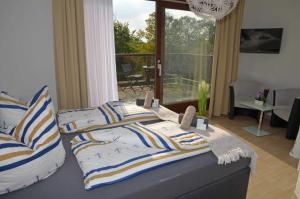 a bedroom with a bed with striped pillows and a balcony at Hotel Neptuns Ankerplatz in Cuxhaven