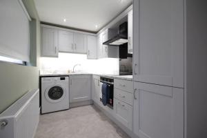 eine weiße Küche mit einer Waschmaschine und einer Waschmaschine in der Unterkunft House in the Gaeltacht Quarter in Belfast
