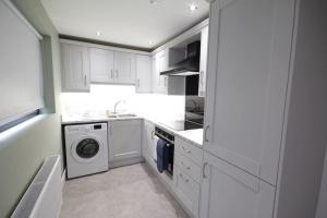 una cocina blanca con lavadora. en House in the Gaeltacht Quarter, en Belfast