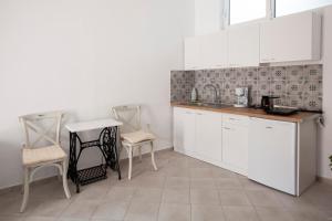 a kitchen with white cabinets and a table and chairs at Hara's Studio in Perdika