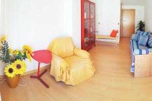 Casa de Praia acolhedora/ Cosy beach house في Marinha das Ondas: غرفة معيشة فيها كرسي اصفر وطاولة