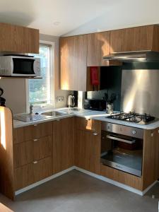 a kitchen with wooden cabinets and a stove top oven at Mobil Home La Palmyre Camping Bonne Anse 4 étoiles in Les Mathes