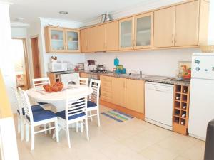 Casa de Praia acolhedora/ Cosy beach house في Marinha das Ondas: مطبخ بطاولة بيضاء وثلاجة بيضاء