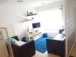 sala de estar con 2 sillas y alfombra azul en Casa de Praia acolhedora/ Cosy beach house, en Marinha das Ondas