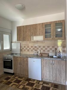 een keuken met houten kasten en een witte koelkast bij Ivana apartman in Vrnjačka Banja