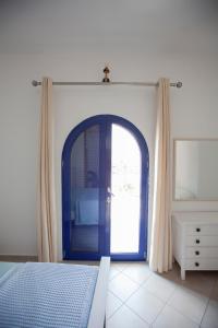 a bedroom with a blue door and a mirror at Hara's Studio in Perdika