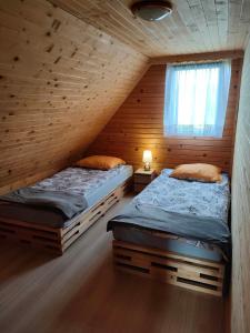 2 camas en una cabaña de madera con ventana en Domek Świerkowy Zakątek en Olchowiec
