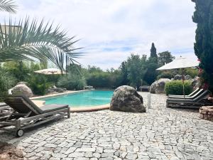 uma piscina com duas espreguiçadeiras e um guarda-sol em Corsicatours Villa em Porto-Vecchio