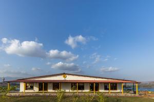 a building with a large roof on top of a field at The Hosteller Bhandardara in Bhandardara 