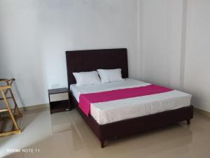 een slaapkamer met een bed met een zwart en roze deken bij New White House in Colombo