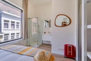 um quarto com uma cama, um espelho e uma mala vermelha em Wonderful apartment in the center of Antwerp em Antuérpia