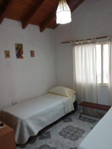 Habitación blanca con cama y ventana en El Parralito hospedaje en Ciudad Lujan de Cuyo