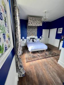 LanouailleにあるMaison de Mags & Mags Willow Roomのベッドルーム1室(青い壁とウッドフロアのベッド1台付)