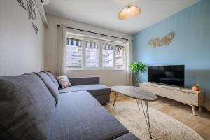 a living room with a couch and a tv at Cosy Morning - L'Azur - Plage 100mètres in Cagnes-sur-Mer