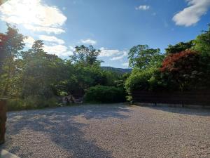 a gravel driveway with trees and a wooden fence at Gynack Villa in Kingussie