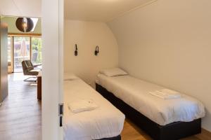 Cette petite chambre comprend 2 lits et un bureau. dans l'établissement 't Landgoed Baars, à Baars