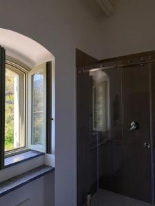 a bathroom with a glass shower with a window at Casello 79 Rais in Finale
