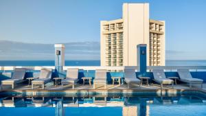 einen Pool mit Stühlen und ein Gebäude in der Unterkunft Pacific Monarch Hotel in Honolulu