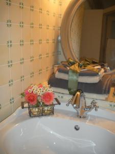 un lavabo con espejo y flores. en Ferme Saint Joseph, en Le Fousseret