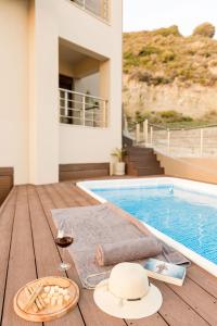 a table with a hat and glasses of wine next to a swimming pool at Halide Luxury Villa in Ixia