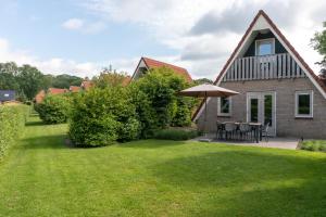 un patio con una casa y una sombrilla en Vakantie bij Meeussen - Molendal en Plasmolen