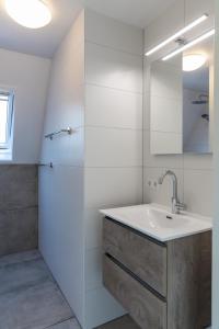 een witte badkamer met een wastafel en een spiegel bij Vakantie bij Meeussen - Molendal in Plasmolen