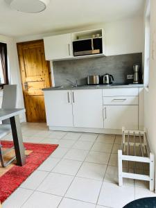 a kitchen with white cabinets and a red rug at Ferienhaus in Rostock - Brinckmansdorf in Rostock