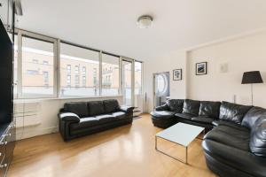 a living room with black leather couches and a table at Pass the Keys Stunning balcony apartment - Central East London in London