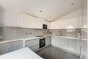 a white kitchen with white cabinets and a sink at Pass the Keys Stunning balcony apartment - Central East London in London