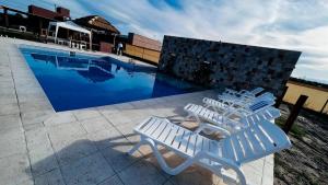 two white chairs sitting next to a swimming pool at ARAUCARIA Resort in San Rafael