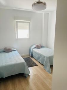 マルベーリャにあるHappy holidaysの白い部屋で、ベッド2台、窓が備わります。