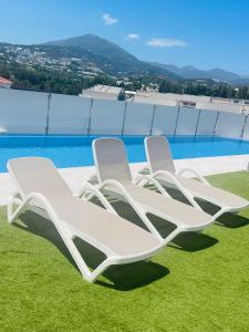 dos sillones blancos sentados en el césped junto a una piscina en Happy holidays en Marbella