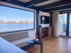 a living room with a large window and a television at Hausboote am Lankenauer Höft in Bremen