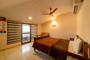 a bedroom with a bed with a ceiling fan and a window at Mermaid Island Beach Resorts in Puducherry