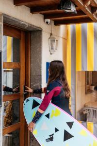 a woman holding a surfboard in front of a door at Pensión Zumardi in Deba