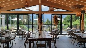 a dining room with tables and chairs and windows at Hôtel Restaurant Le Repère in Vizille